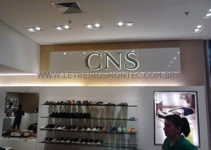 Letreiro da loja CNS de cal&ccedil;ados em a&ccedil;o inox polido e iluminado por leds em ambiente interno